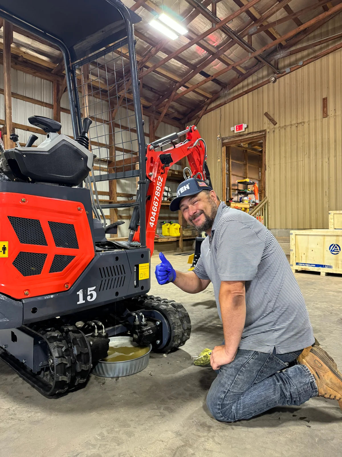 GHM team member beside a red mini excavator in the workshop